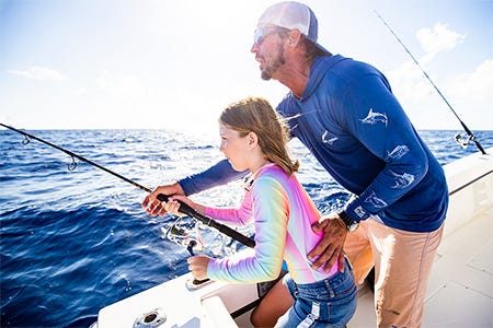 a captain guiding a little kid on how to reel in a fish